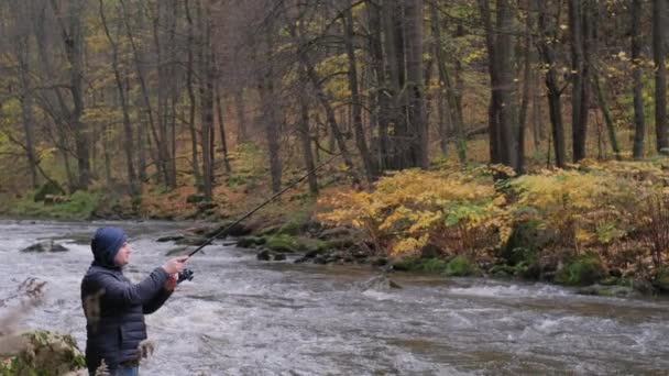一个渔夫拿着钓竿 转动着钓竿柄 一个人在山河里钓鱼 — 图库视频影像