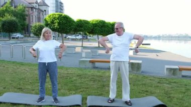 Şehir parkında egzersiz yapan gülümseyen yaşlı bir çiftin portresi..