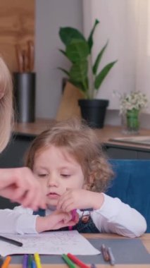 Büyük anne ve küçük torun renkli kalemlerle kağıt üzerinde bir araya gelirler. Anaokulu aktivitesi, bebek bakıcılığı konsepti. Dikey video