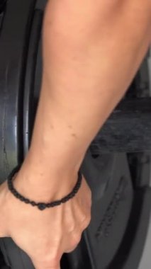 Spor salonunda ağırlık çalışması. Bir kadın antrenman yapıyor. Halter çöker. Dikey video.