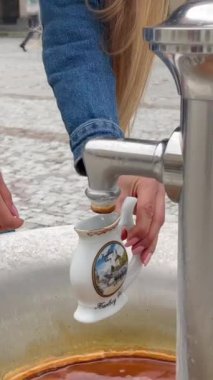 Güzel bir kız, Çek Cumhuriyeti 'nin Karlovy Vary kentindeki doğal bir kaplıcada bir bardağa şifalı maden suyu dolduruyor. Karlovy Vary tarihsel olarak kaplıcalarıyla tanınır. Dikey video