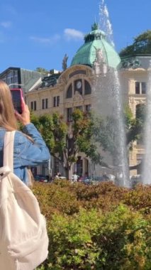 Genç bir kadın eski kasabanın sokaklarında yürüyor. Yürüyüş turları. Dikey video.