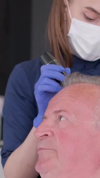 一位戴放大镜的三叶虫学家检查了一个脱发病人的头部 去看一位三位一体的医生垂直录像 — 图库视频影像