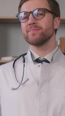 Kütüphanede doktor önlüğü giymiş bir öğrenci. Kitabın arka planında. Eğitimdeki stajyer. Dikey video.
