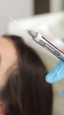 Diş hekimi elinde şırıngayla hastasını uyuşturuyor. Diş hekiminin muayenehanesinde elinde diş şırıngası tutan bir dişçinin yakın çekimi. Dikey video