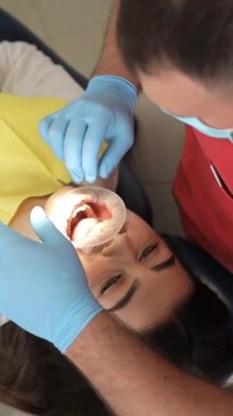 Dişçi modern diş kliniğindeki hastalar için kauçuk genişletici kullanıyor. Diş hekimliğinde Cofferdam. Dikey video