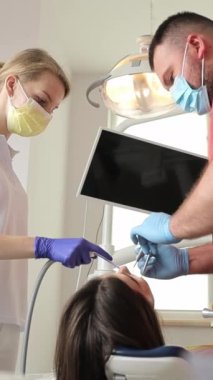 Bir dişçi modern bir klinikte dişleri tedavi eder. Dişlerin ağrıyor. Acısız diş tedavisi. Dikey video.