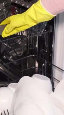 Kadın el dolgusu, kirli tabakları yerleştirme, yerleştirme, beyaz tabakları açık otomatik bulaşık makinesine yerleştirme görüntüsünü kapatın. Ev hanımı ev işlerini yapar. Dikey video.