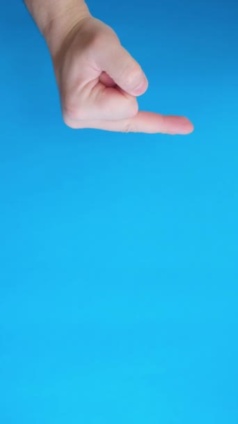 用蓝色背景的中指紧闭负手手势 垂直录像 — 图库视频影像