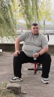 Parkta egzersiz yapan kilolu bir adam. Açık havada çalışan iri yarı beyaz bir erkek. Motivasyon disiplini kavramı. Kilo kaybı. Dikey video