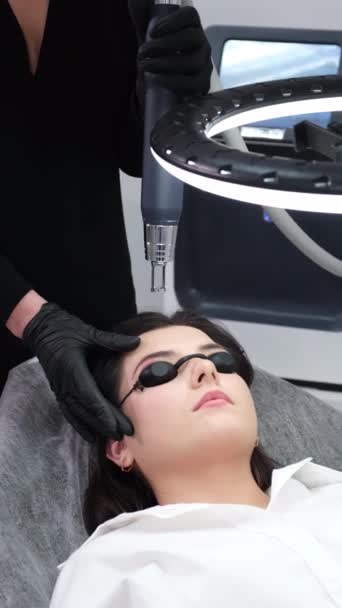 サロンの若い女性の永久的な構造の眉毛のレーザーの取り外し ビューティーサロンでカーボンフェイスピーリング ハードウェア化粧品の治療 バーティカルビデオ — ストック動画