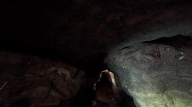 Profesyonel bir arkeolog karanlık bir mağarayı aydınlatır ve araştırır. Arkeoloji kavramı.