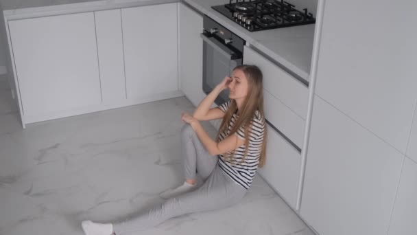 Κουρασμένη Γυναίκα Που Κάθεται Στο Πάτωμα Στο Δωμάτιο Της Κουζίνας — Αρχείο Βίντεο