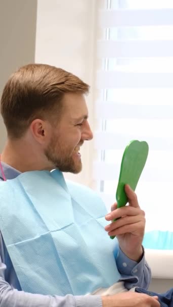 Симпатичный Пациент Мужчина Смотрящий Свою Прекрасную Улыбку Сидя Стоматологическом Кабинете — стоковое видео