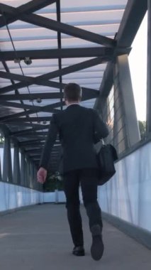 Çantası olan bir iş adamı hızla ofise koşar. Dikiz aynası. Elinde evrak çantası olan siyah takım elbiseli bir işadamı bankada çalışmak için acele ediyor. Dikey video.