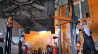 Araba servisinde çalışan bir tamirci. Arabanın altında profesyonel bir tamirci. Modern araba atölyesi.