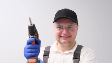 Elinde elektrikli matkapla beyaz bir arka planı olan bir inşaatçı..