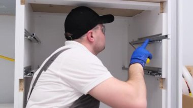 Mutfak profesyonel bir zanaatkar tarafından kurulmuş. Sanatçı mutfak dolabının kapısının menteşesini ayarlar.. 