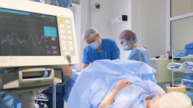 Ameliyat sırasında cerrahi laparoskopi aletleri kullanarak bacak damarlarını kesen bir cerrah ekibi..
