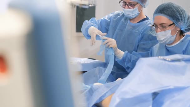 手术期间 病人在手术台上的腿上安装了用于静脉射频凝固的导管 医生和助手对静脉曲张进行外科治疗 — 图库视频影像