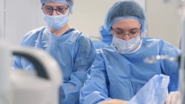 手術中に外科医のチームが手術用腹腔鏡検査器を使用して脚静脈を除去する — ストック動画