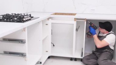 Tulum giymiş, yeni mutfak mobilyalarını içeri kurmakla meşgul. Mutfak mobilyası koleksiyonu.