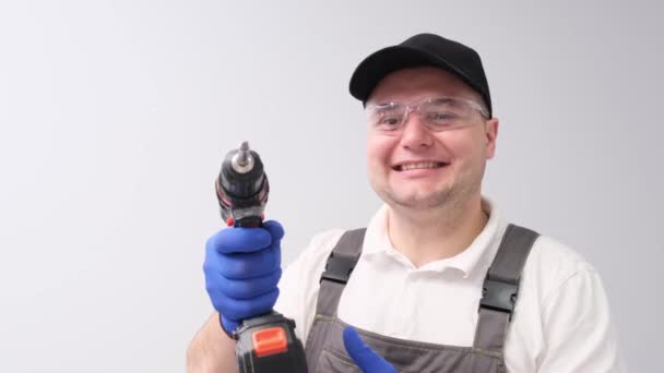 一个面带微笑的工人 手里拿着电钻 背景是白色的 — 图库视频影像