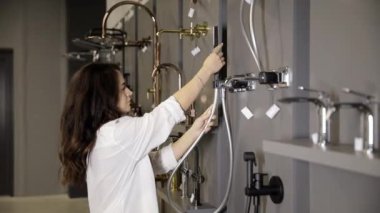  Müşteri, hırdavatçıda duş musluğu seçer. Alıcı, tesisat cihazının kullanılabilirliğini kontrol ediyor..