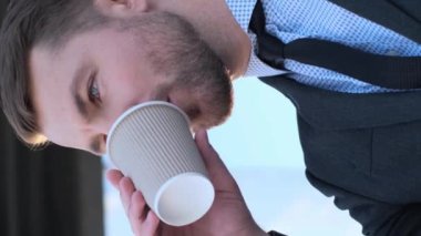 Genç bir işadamı kahve içer. Kahve molası zamanı. Yakın plan. Dikey video. İş adamı dışarıda kahve içiyor..