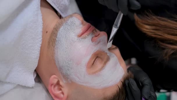 Kosmetyk Nakłada Maskę Nawilżającą Twarz Mężczyzny Mężczyzna Klinice Kosmetycznej Zbliżenie — Wideo stockowe
