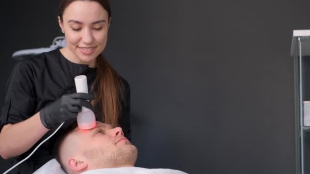 一个在美容院接受电刑的年轻人 男人用按摩来照顾他的脸 — 图库视频影像