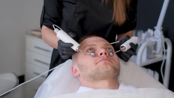 美容和技术概念 年轻男子在温泉中使用微电流紧固装置进行间歇性治疗或面部皮肤水肿 — 图库视频影像