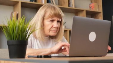 Laptop ve belgelerle uğraşan yaşlı bir kadın. Yetişkin bir kadın. Faturaları internet bankacılığıyla ödüyor.