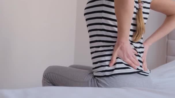 年轻的女孩背痛坐在床上 一个漂亮的女人脊椎或肾脏疼痛 一个女人在家里背痛 — 图库视频影像