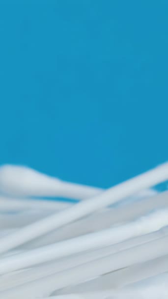 衛生製品 白い綿棒は青い背景の円で回転する スローモーション バーティカルビデオ — ストック動画