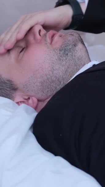 ホテルのベッドに横たわっている白い頭を持つ若い実業家 ミューリン バーティカルビデオ — ストック動画