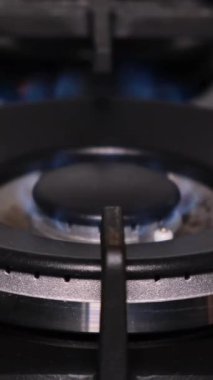 Gaz sobasının yakın plan ateşlemesi. Gaz, karanlık bir odada mavi bir ateşle yanar. Dikey video