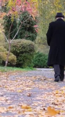 Yalnız yaşlı bir adam sonbahar parkında yürüyor, adımları yavaş ve kararlıydı. Adam depresyonda. Yalnız bir son sınıf öğrencisi. Dikey video