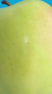 Mavi arka planda izole edilmiş mükemmel taze yeşil elma. Meyve, sağlıklı yiyecek. Dönen elmayı kapat. Dikey video.