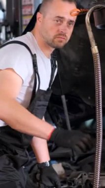 Arabanın yağını değiştiriyorum. Araba servisinde çalışırken araba tamircisi. Dikey video.