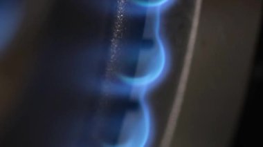 Gaz sobasının yakın plan ateşlemesi. Gaz, karanlık bir odada mavi bir ateşle yanar. Dikey video.