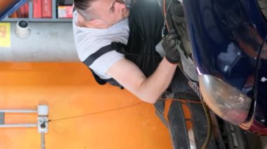 Arabanın yağını değiştiriyorum. Araba servisinde çalışırken araba tamircisi. Dikey video.