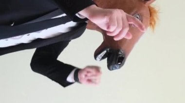 At maskesi takmış dans eden genç bir adam ritmik olarak ellerini stüdyonun arka planında yukarı kaldırıyor. Dikey video
