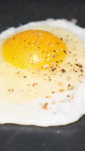 卵をパンの上で揚げる クッキング 朝ごはんについて クローズアップ バーティカルビデオ — ストック動画