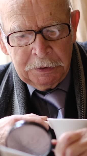 一位年迈的意大利绅士正坐在椅子上的咖啡店里 一边喝咖啡 一边看报纸 垂直录像 — 图库视频影像