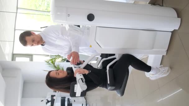 垂直录像 一个专业的脊椎专家和一个女人一起在一个背操机器上训练 对背部疾病的治疗 垂直录像 — 图库视频影像