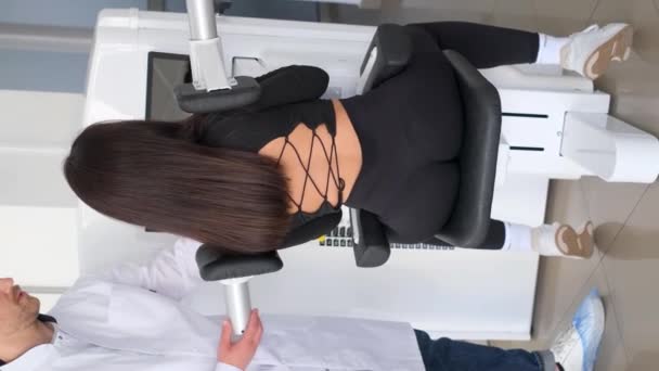バーティカルビデオ 背中のエクササイズマシンの女性と一緒に専門の脊椎科医の列車 背中の病気の治療 バーティカルビデオ — ストック動画
