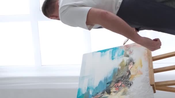 一位画家在画布上画了一幅画 画上画的是家中的彩绘油画 一位艺术家在车间里创作并创造性地创作了一幅抽象油画 Hobby的概念 垂直录像 — 图库视频影像