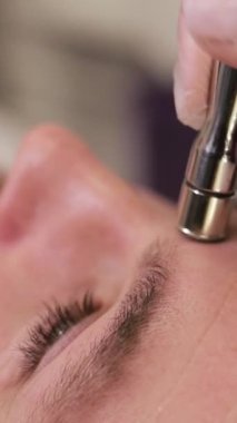 Kozmetik yüz bakımı. Salondaki genç yakışıklı adam. Dermatolojik elmas cilt temizleme. Kapatın. Estetik yüz bakımı prosedürü. Dikey video