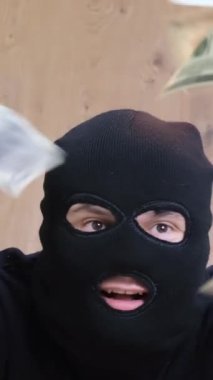 Siyah maskeli bir soyguncu kasadan para alır. Soygun tehlikesi. Dikey video.